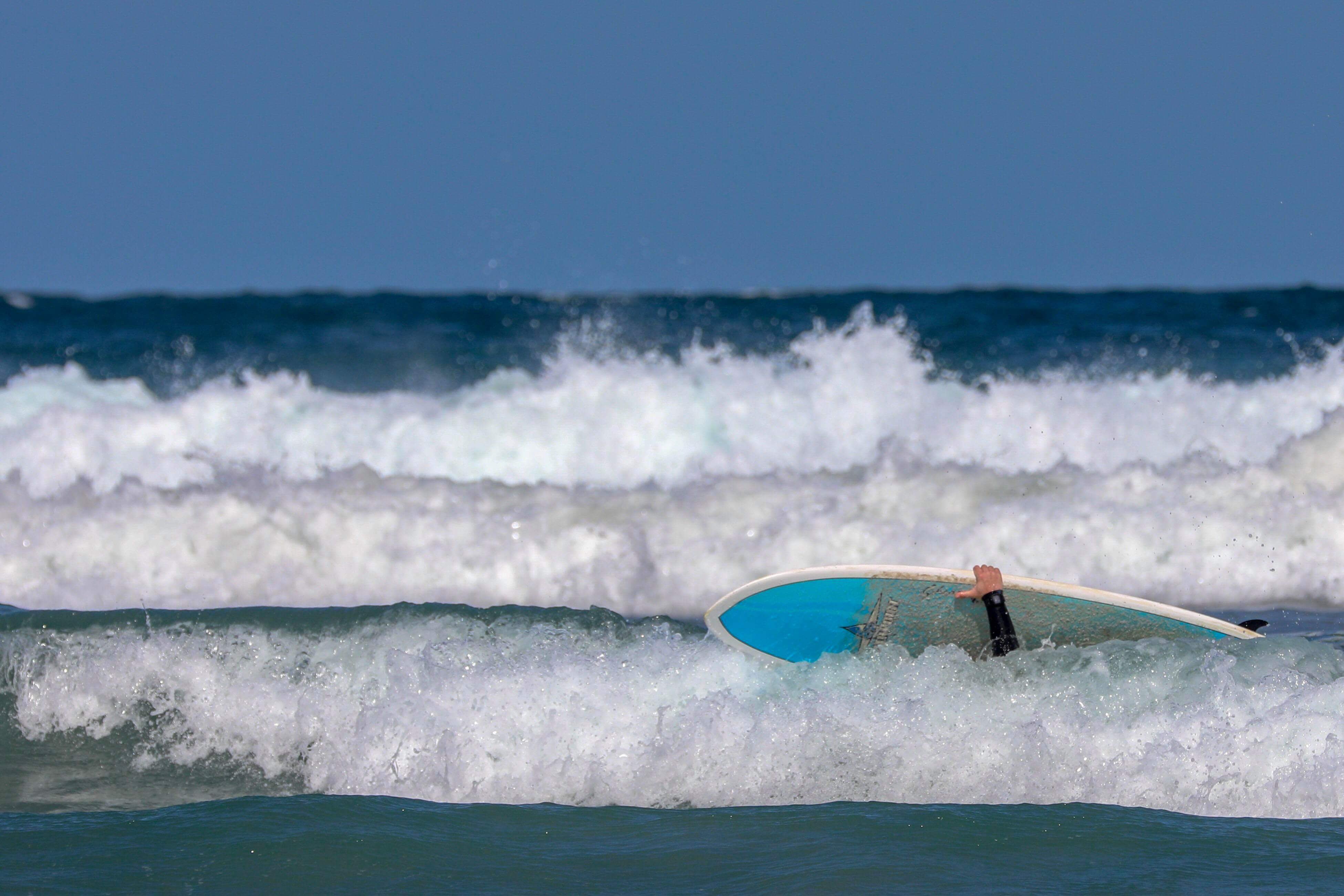 Xisco in the whitewater at his first surf school, holding on to his board